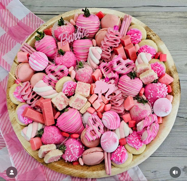 a wooden platter filled with lots of pink and red candy hearts on top of a checkered table cloth