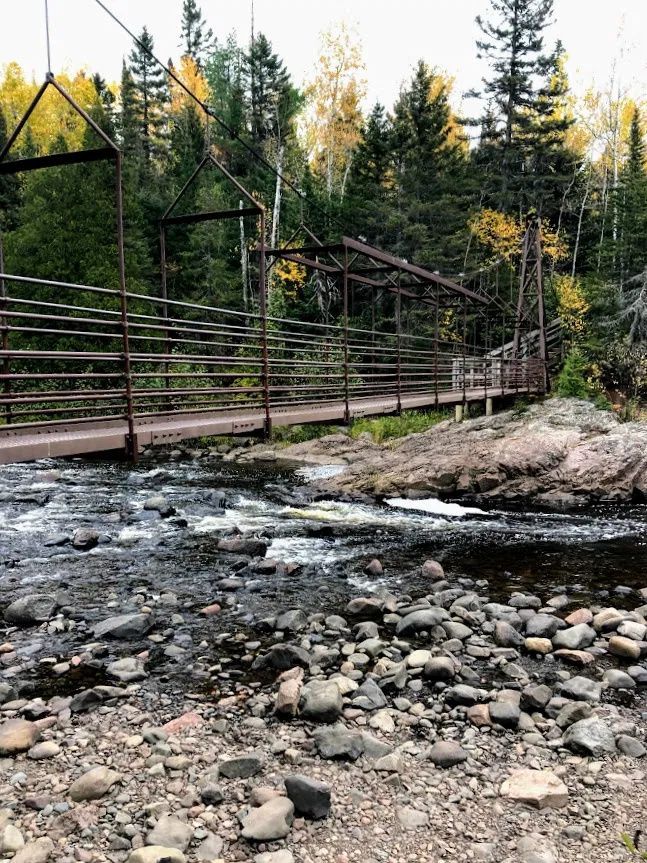 a bridge over a river with rocks and trees in the backgroung area