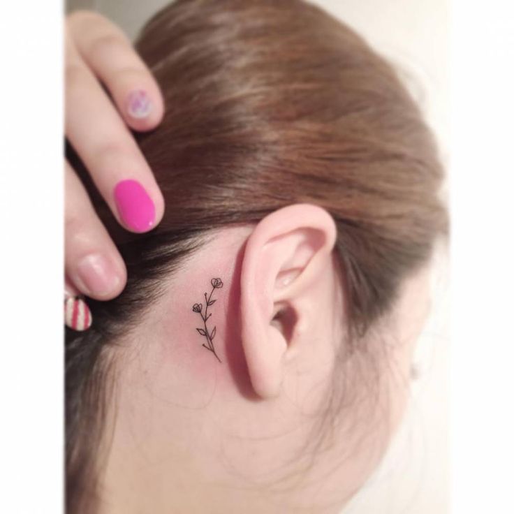 a woman's ear with a small flower tattoo on it