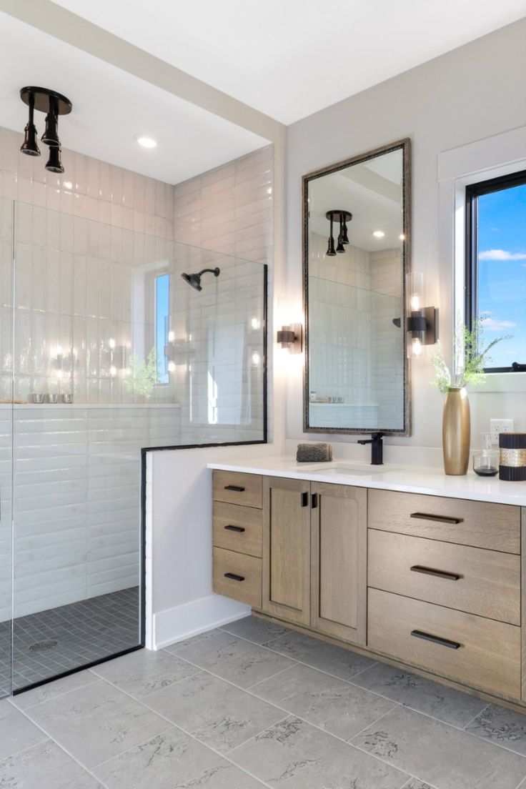 a large bathroom with two sinks, mirrors and a walk - in shower next to a window