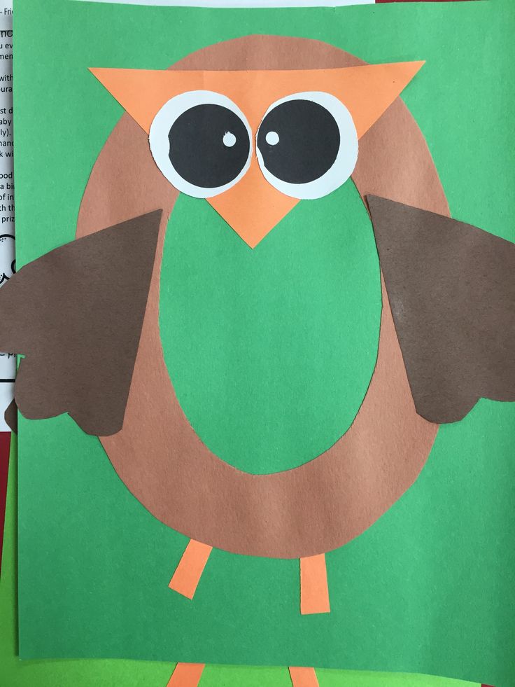 an owl made out of paper sitting on top of a green piece of paper with scissors