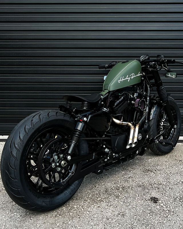 a green motorcycle parked in front of a garage door next to a black metal wall