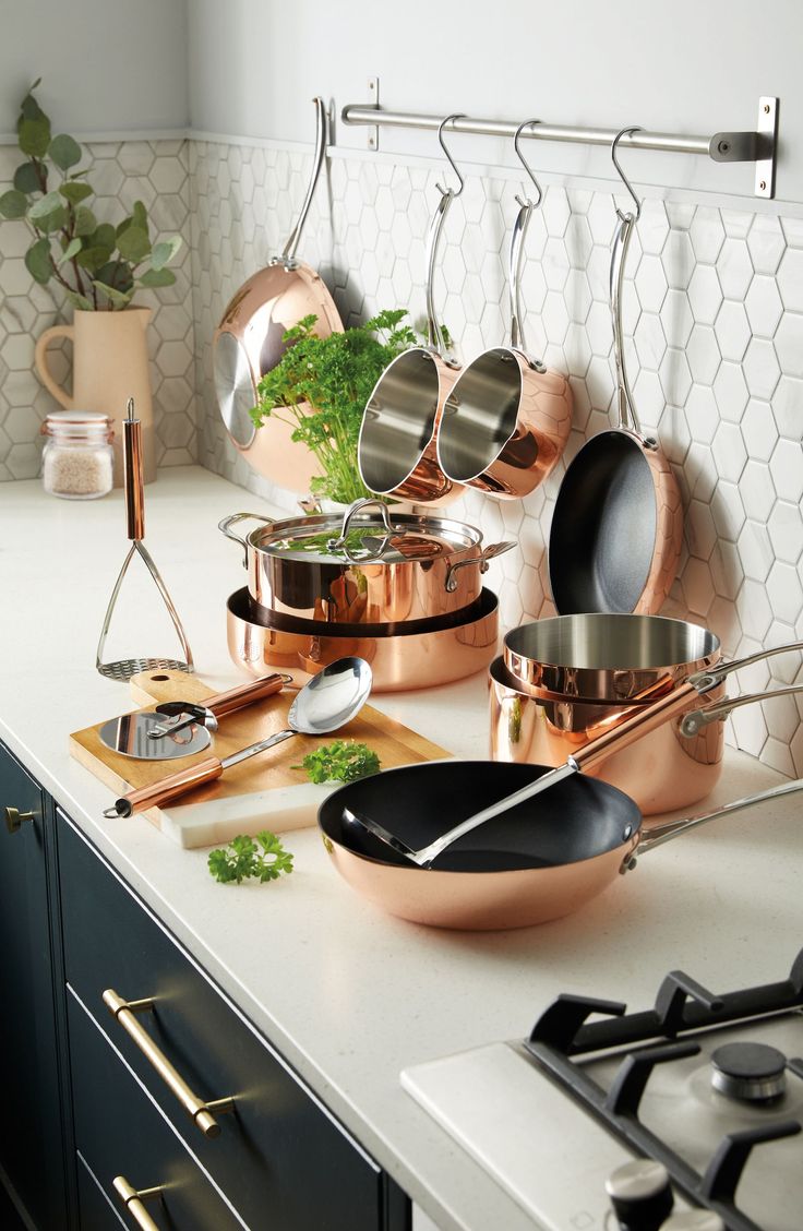 pots and pans are lined up on the kitchen counter top with utensils