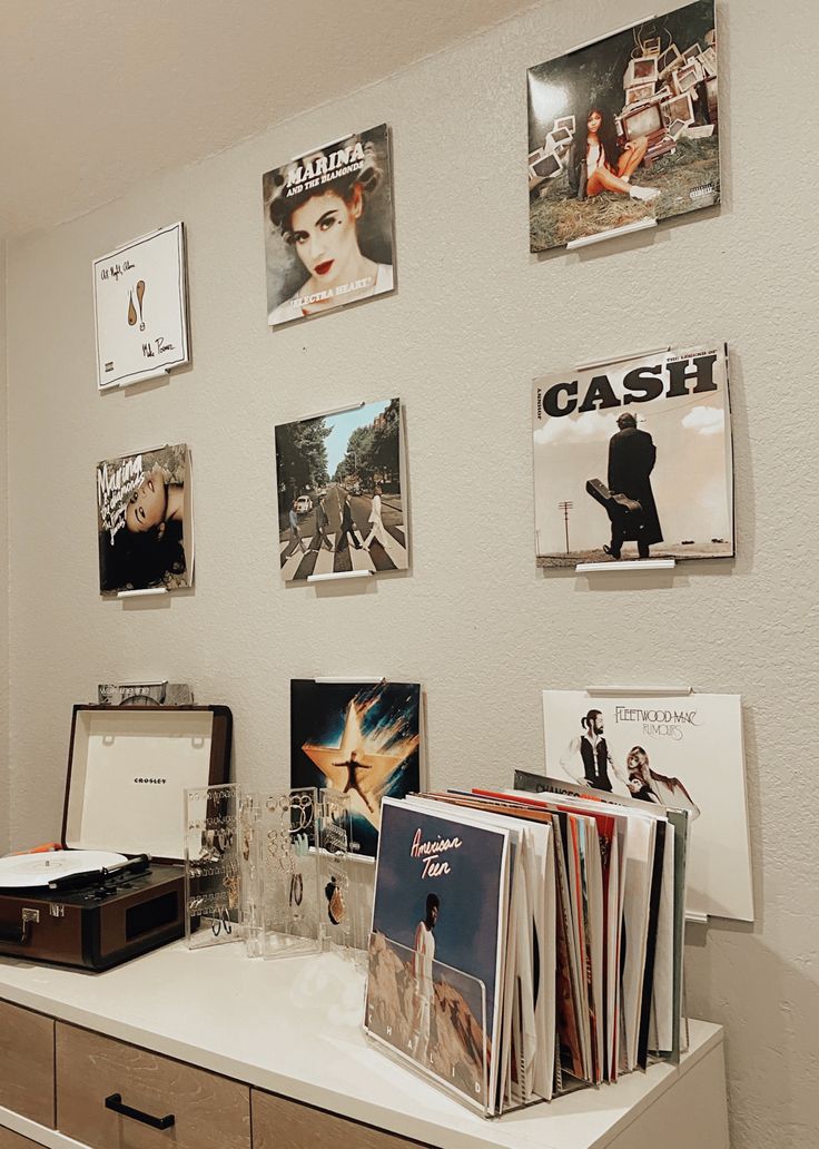 a desk with records, cds and other items on it in front of a white wall