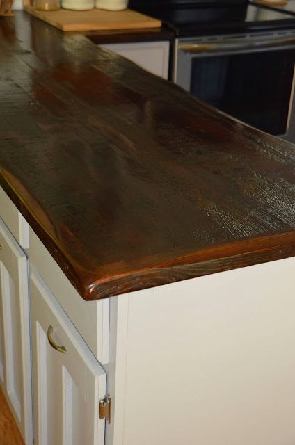 a counter top in a kitchen with white cabinets and wood flooring on the walls