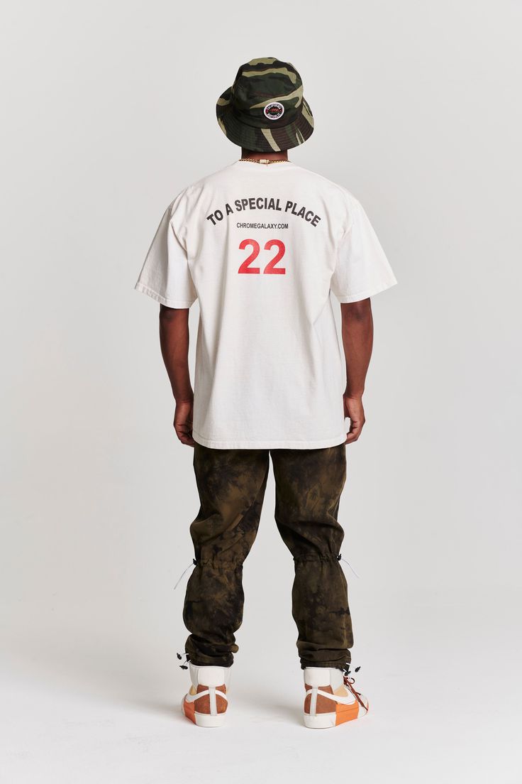 Short sleeve t-shirt in creme with kid swirling down in the front and number print featured in the back. Cotton Short Sleeve Fan Apparel T-shirt, Sports Fan Apparel T-shirt With Short Sleeves, Fan Apparel T-shirt For Sports Events, Short Sleeve T-shirt With Text Print For Streetwear, College Fan Apparel T-shirt Short Sleeve, Casual Streetwear Shirt With Crew Neck, Casual Crew Neck Shirt For Streetwear, Cotton Short Sleeve Top For Streetwear, Streetwear Graphic Tee With Short Sleeves