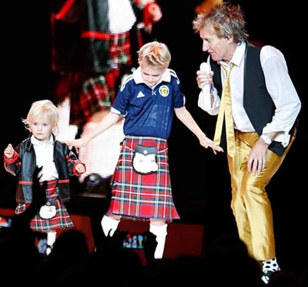 two children and an adult on stage with one holding the hand of another child's hand