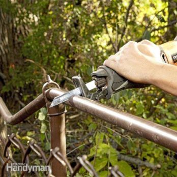 a man is using a power tool to trim a metal rail in front of some trees