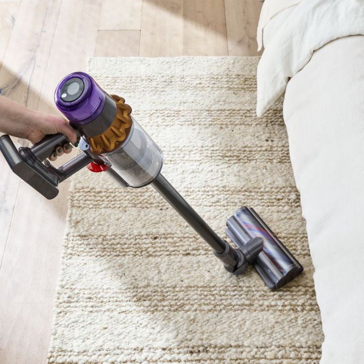 a person using a vacuum cleaner on a rug