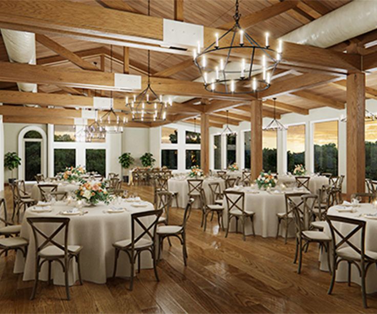 a large room with tables, chairs and chandeliers on the ceiling is set for an event