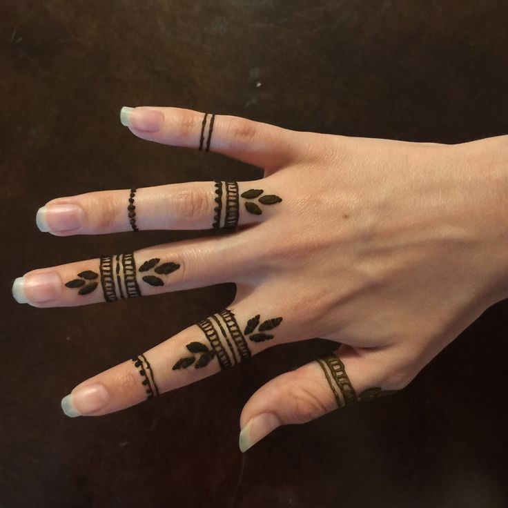 a woman's hand with four rings on it and two fingers, both decorated with leaves