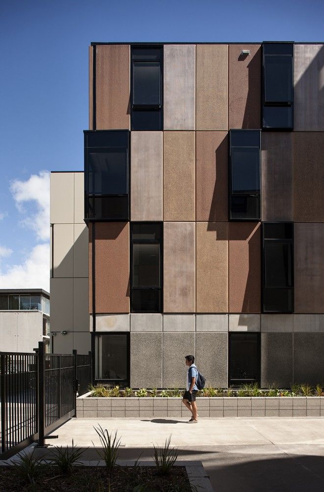 a person walking in front of a tall building with lots of windows on the side