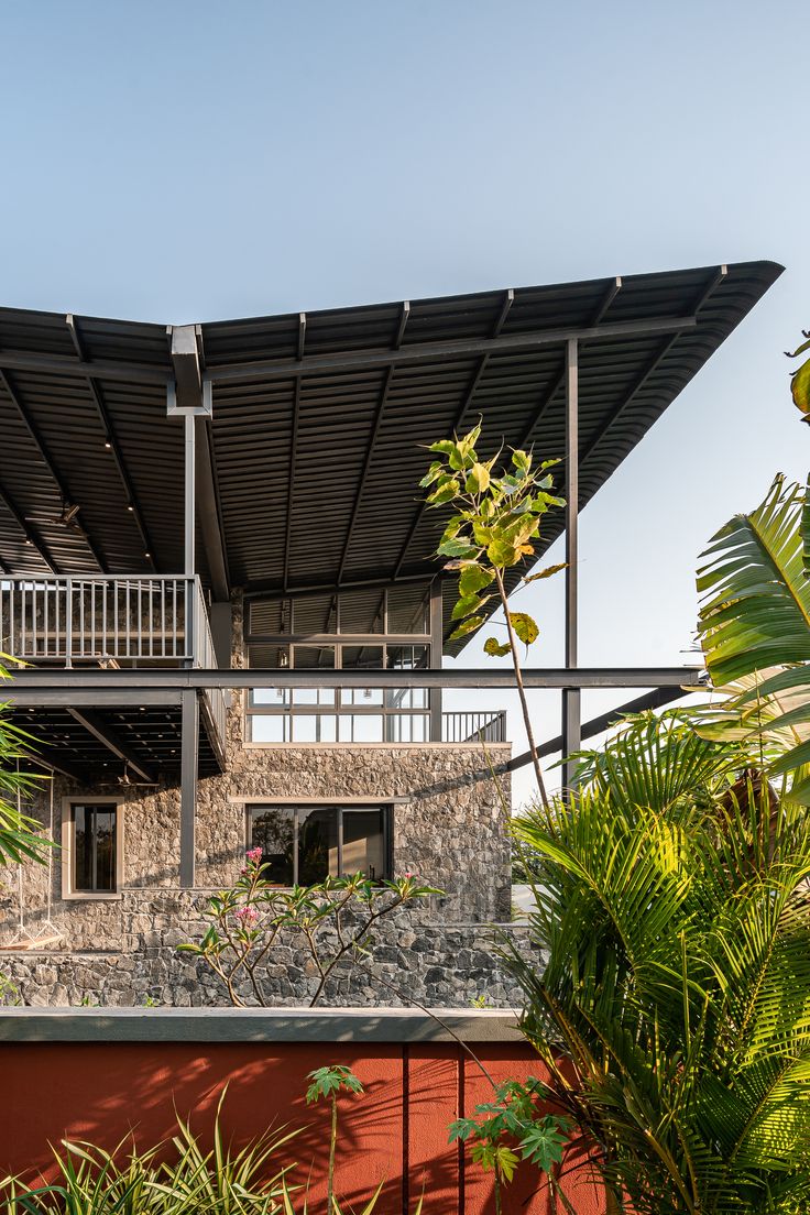 a house with a roof made of metal and surrounded by greenery on the outside