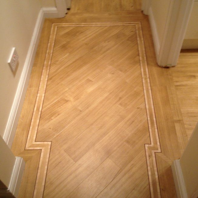 an empty hallway with hard wood floors and white trim