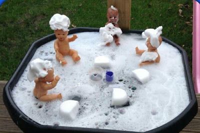 some toys are sitting in the sand and playing with it's water inside an ice bucket