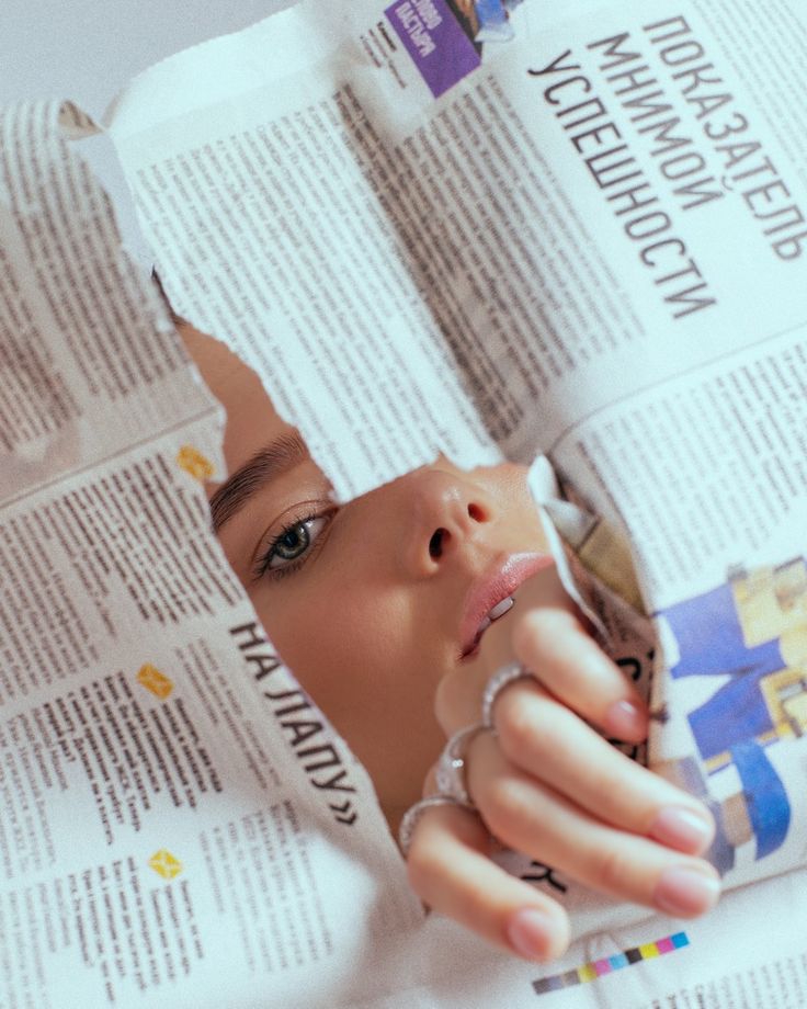 a woman looking through a hole in a newspaper