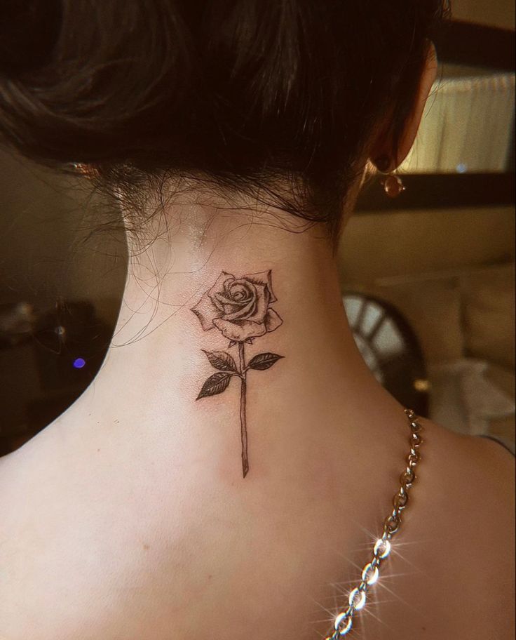 a woman's neck with a rose tattoo on her left side ribcage