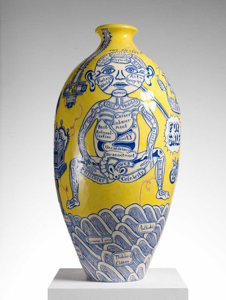 a yellow and blue vase with an image of a monkey on the front, surrounded by words