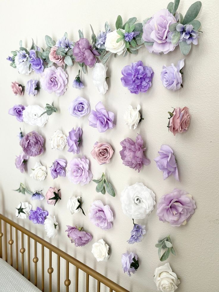 a baby crib with purple and white flowers hanging on the wall next to it