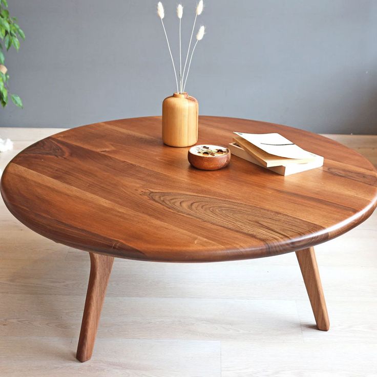 a wooden table topped with a vase and two reeds on it's legs