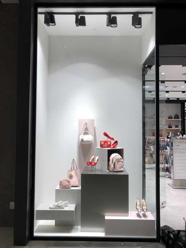 a display window with shoes and bags in the front, lights on behind it to illuminate people's attention