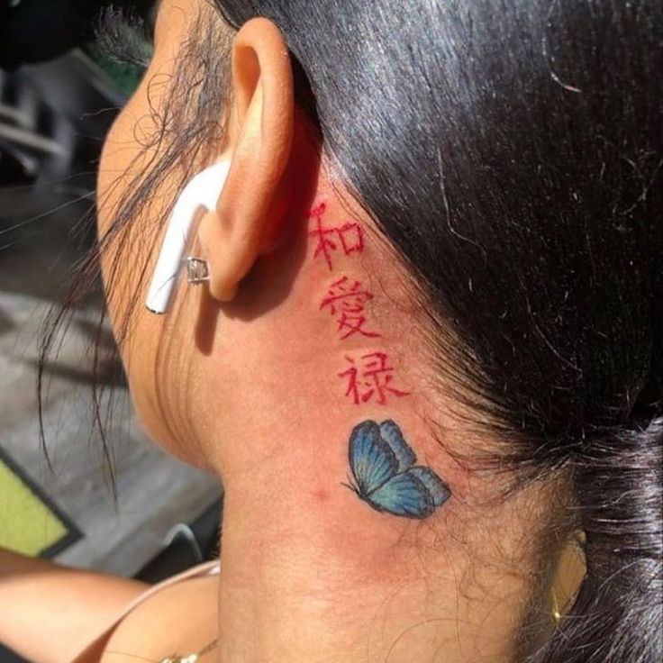 the back of a woman's head with tattoos on her neck and behind her ear