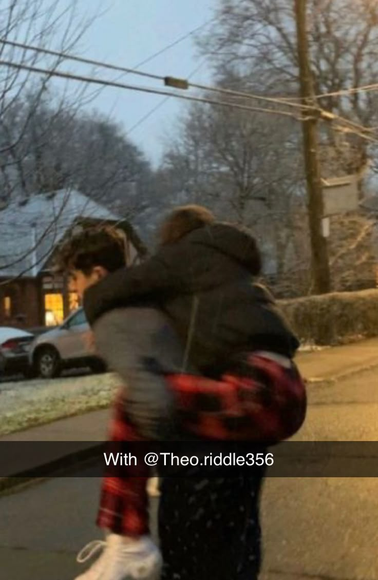 two people are walking down the street in the snow with their arms around each other