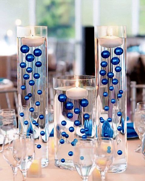 a table topped with lots of blue glass vases filled with candles