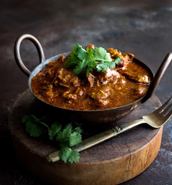 a bowl filled with meat and garnished with cilantro on top of a wooden board