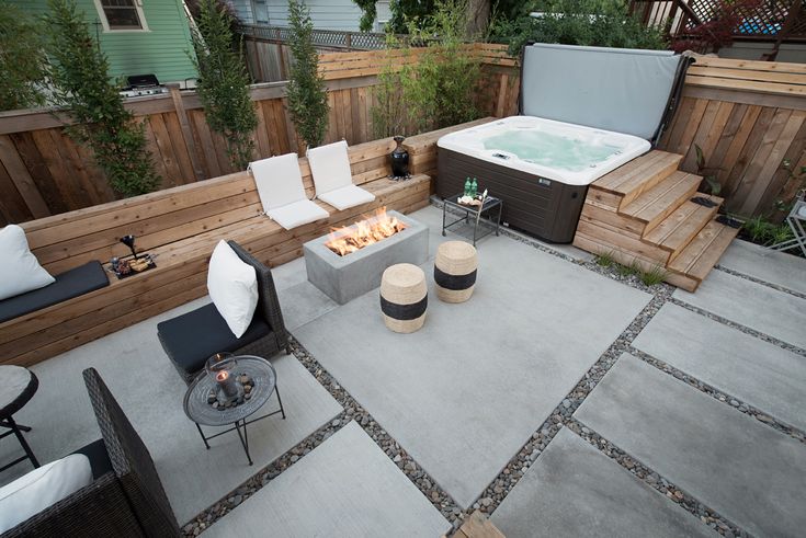 a hot tub sitting on top of a cement patio next to a fire pit and seating