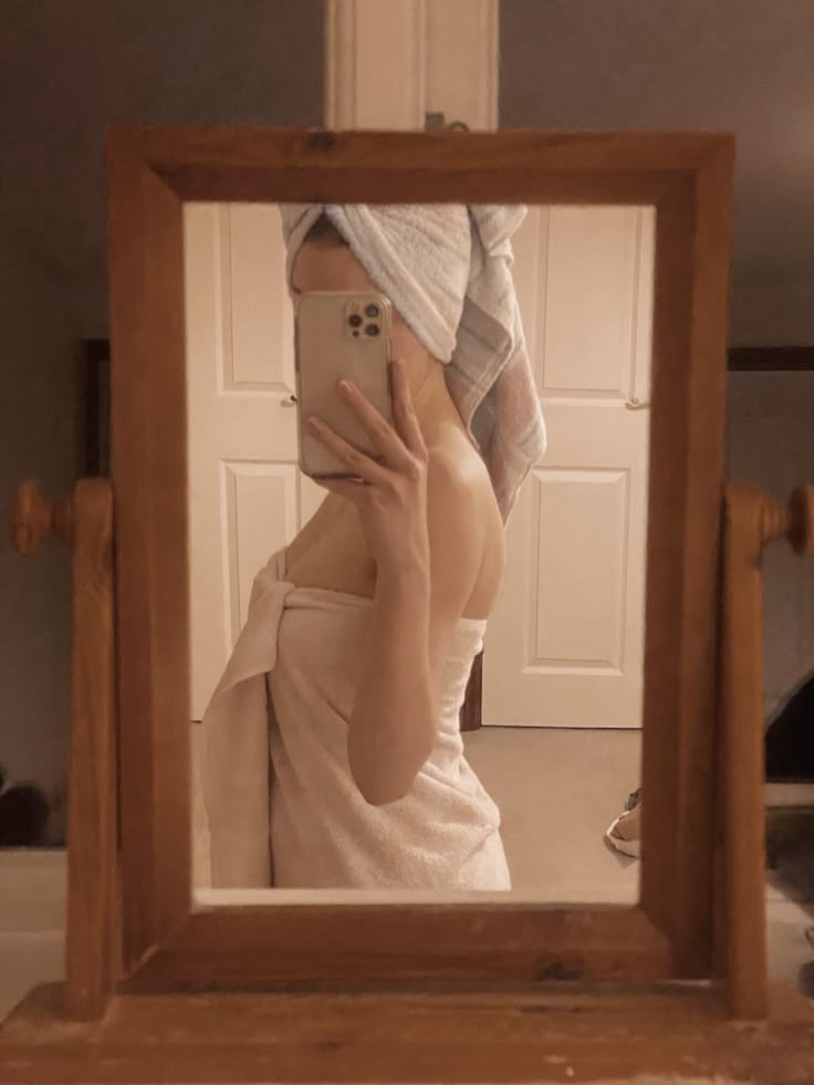 a woman taking a selfie in front of a mirror with her hand on the phone