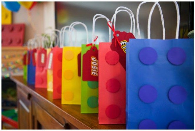 colorful bags are lined up on a table with balloons in the background and one has a price tag