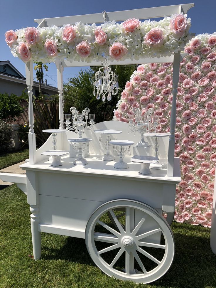 an ice cream cart decorated with pink roses and chandeliers for a wedding reception