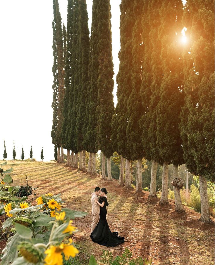 a bride and groom standing in front of sunflowers