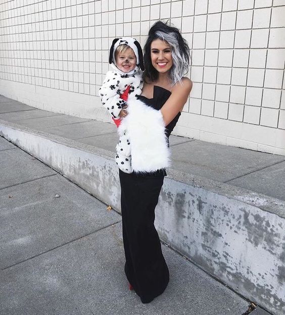 a woman holding a child dressed in dalmatian costumes and posing for the camera