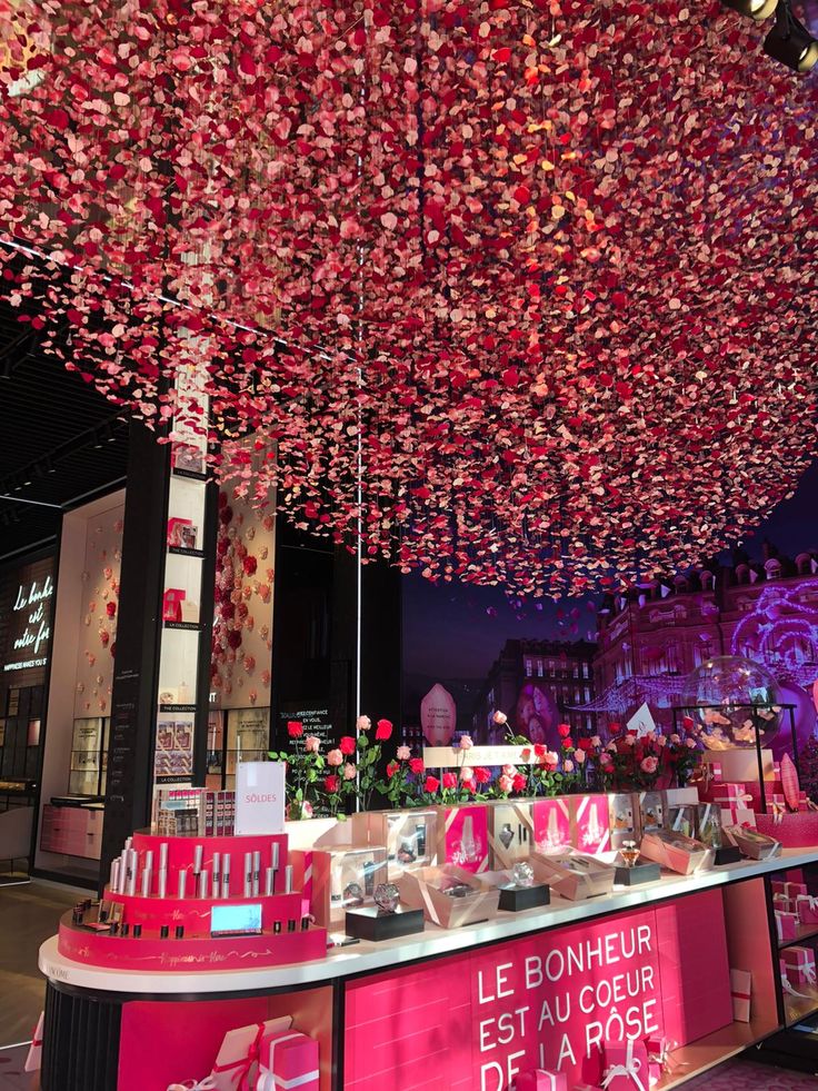 a pink counter with lots of flowers hanging from it's ceiling in a mall