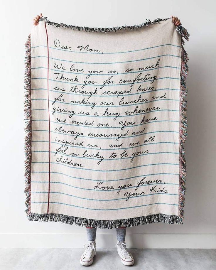 a woman holding up a blanket with writing on it