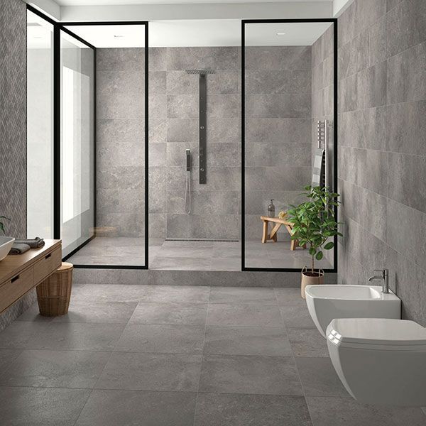 a modern bathroom with grey tiles and black trimming on the walls, along with a plant in the corner