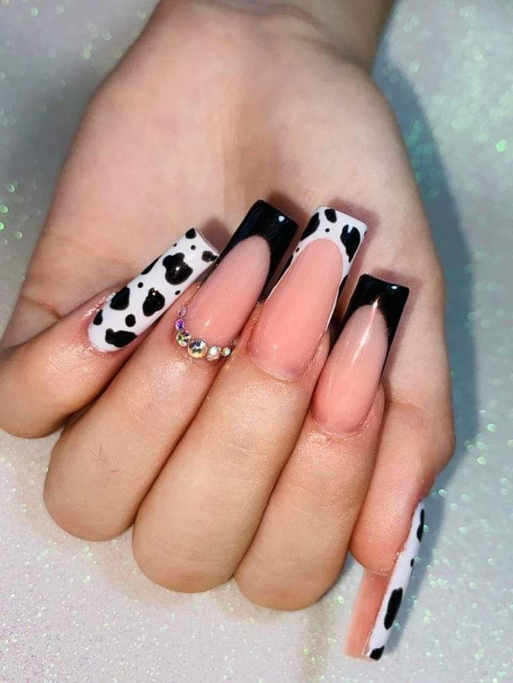 a woman's hand with black and white nail polishes on her nails, holding an animal print manicure