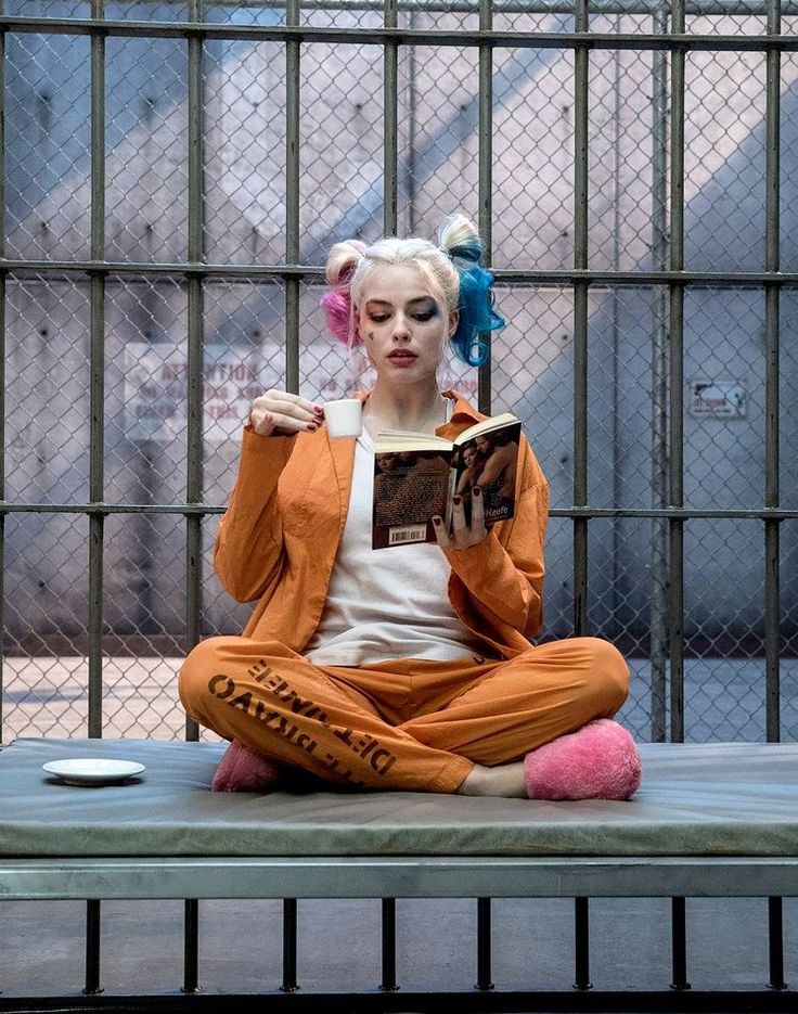 a woman sitting in a jail cell reading a book