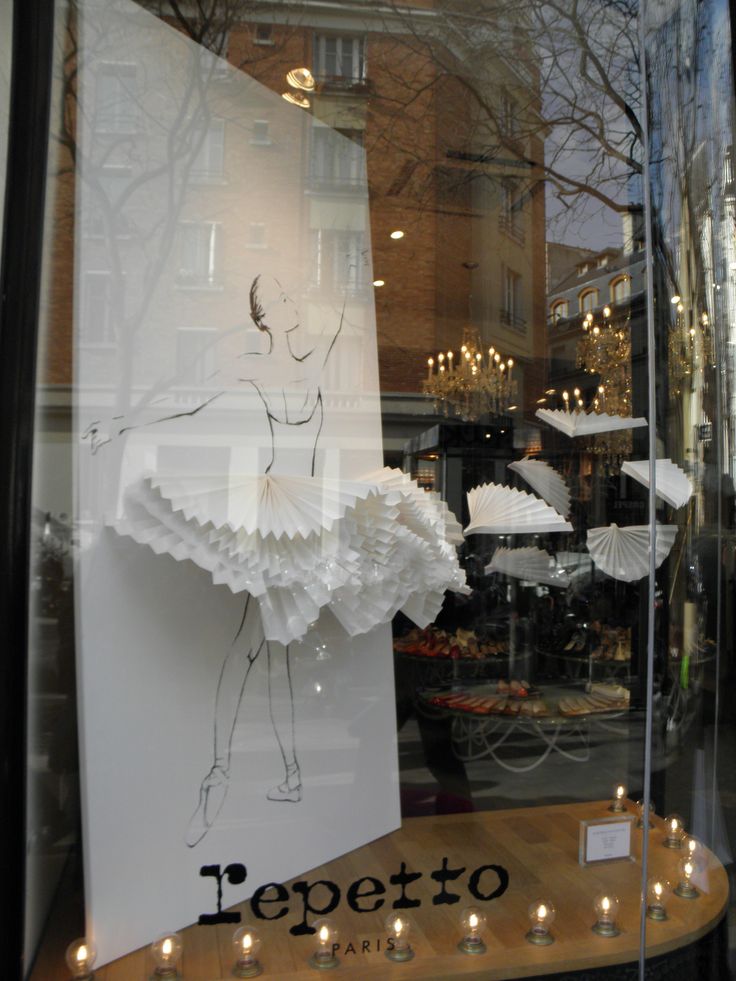 a window display with candles in front of it and an image of a ballerina