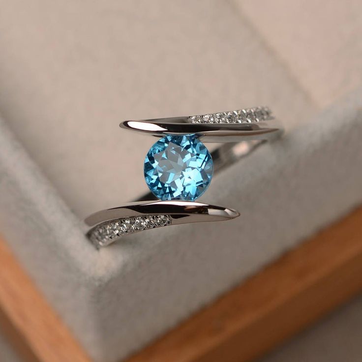 This halo ring features a 6mm round cut Swiss blue topaz and sterling silver finished with rhodium. Customization is available. It is made by hand, and it will take about 7 days to finish the ring after your payment is completed. Main stone: Swiss blue topaz weight: Approx 1.04 ct Metal type: sterling silver finished with rhodium Accent stone: cz Customization is available, I also can make it with 14k solid gold (white or yellow or rose) and diamond accent stone, just feel free to contact me. An Promise Ring Band, Swiss Blue Topaz Ring, Blue Gemstone Rings, Colored Engagement Rings, Topaz Engagement Ring, London Blue Topaz Ring, Sterling Silver Engagement Rings, Silver Engagement Rings, Swiss Blue Topaz