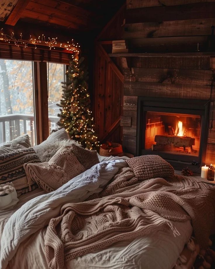 a bed with blankets and pillows in front of a window next to a fire place