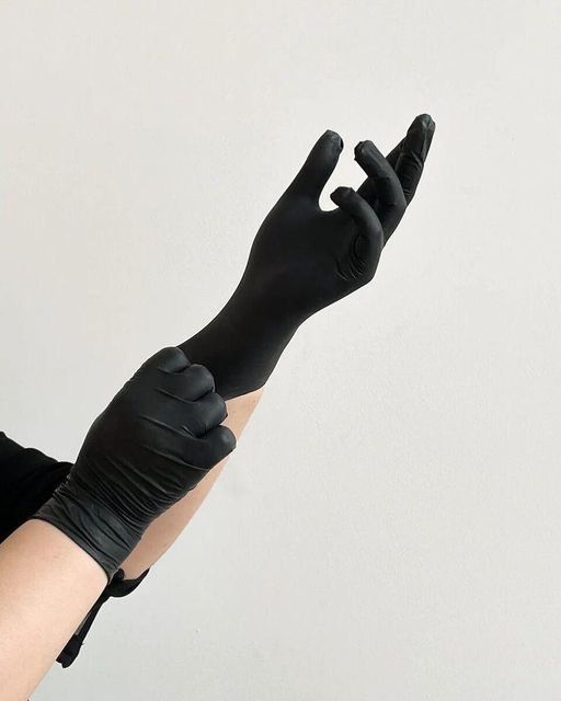 a woman wearing black gloves is holding her hand up