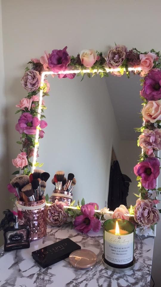 a mirror with flowers and candles on it sitting on a table next to a candle