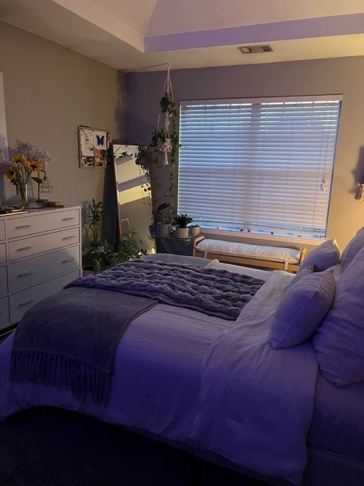 a bedroom with a bed, dressers and window in it's center area