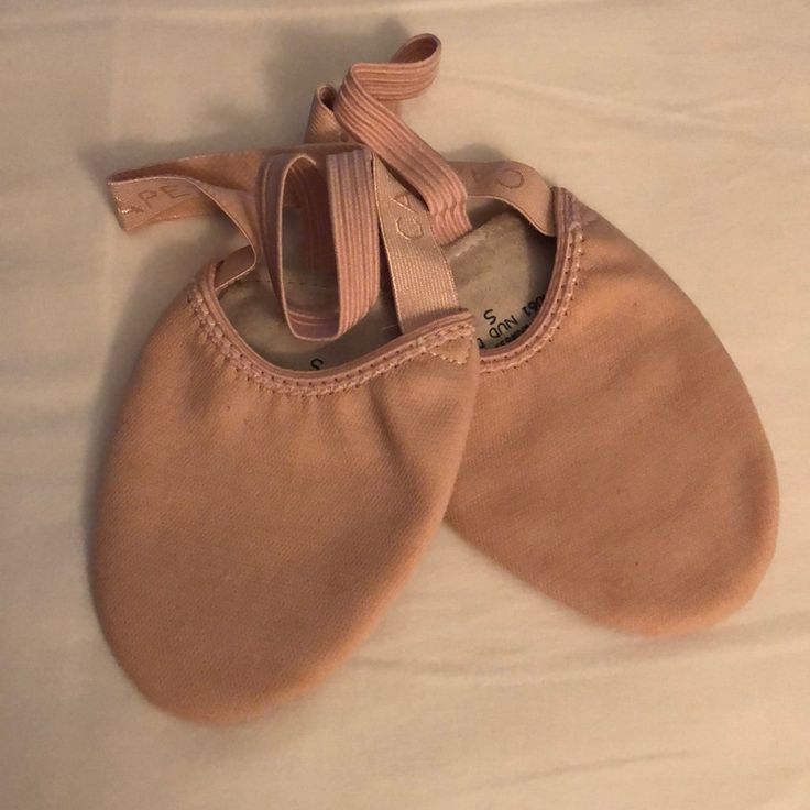 two pairs of baby shoes are laying on the bed together, one is pink and the other is brown