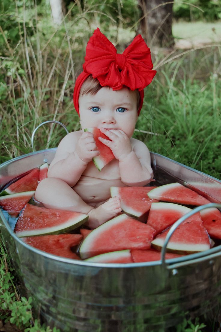 a baby sitting in a bucket with watermelon slices