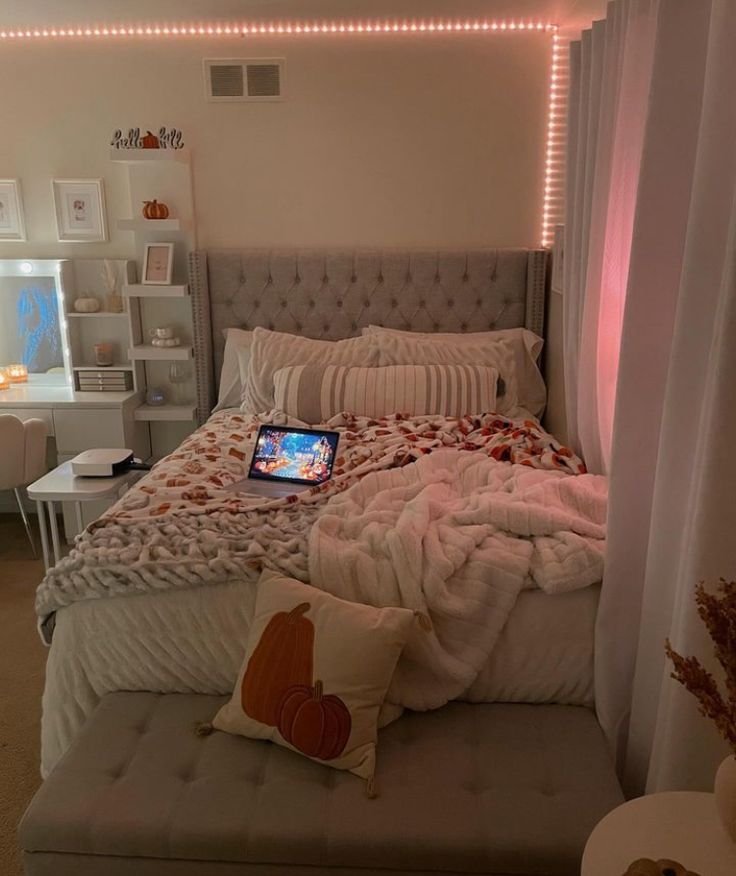 a laptop computer sitting on top of a bed in a room with white walls and curtains