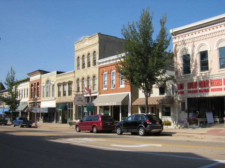 cars are parked on the street in front of shops and businesses, along with trees